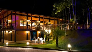 A modern hotel with a two-story structure, outdoor seating area, and a well-lit entrance. - ASA Quinta da Esmeralda Bar Pool Cabins (Itajai)