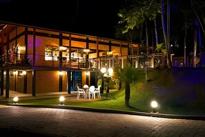 A modern hotel with a two-story structure, outdoor seating area, and a well-lit entrance. - ASA Quinta da Esmeralda Bar Pool Cabins (Itajai)