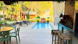 A pool area with lounge chairs, a table, and a bar. - ASA Quinta da Esmeralda Bar Pool Cabins (Itajai)