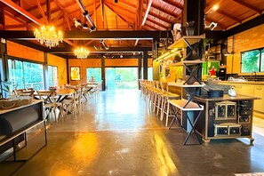 A spacious dining area with high ceilings, exposed beams, and a long counter with stools. - ASA Quinta da Esmeralda Bar Pool Cabins (Itajai)