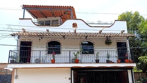A two-story building with a balcony, a garage, and a stone foundation. - Casa Axixic (AJIJIC)