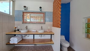 A bathroom with a wooden vanity, two sinks, a mirror with a decorative frame, and a toilet. - Casa Axixic (AJIJIC)