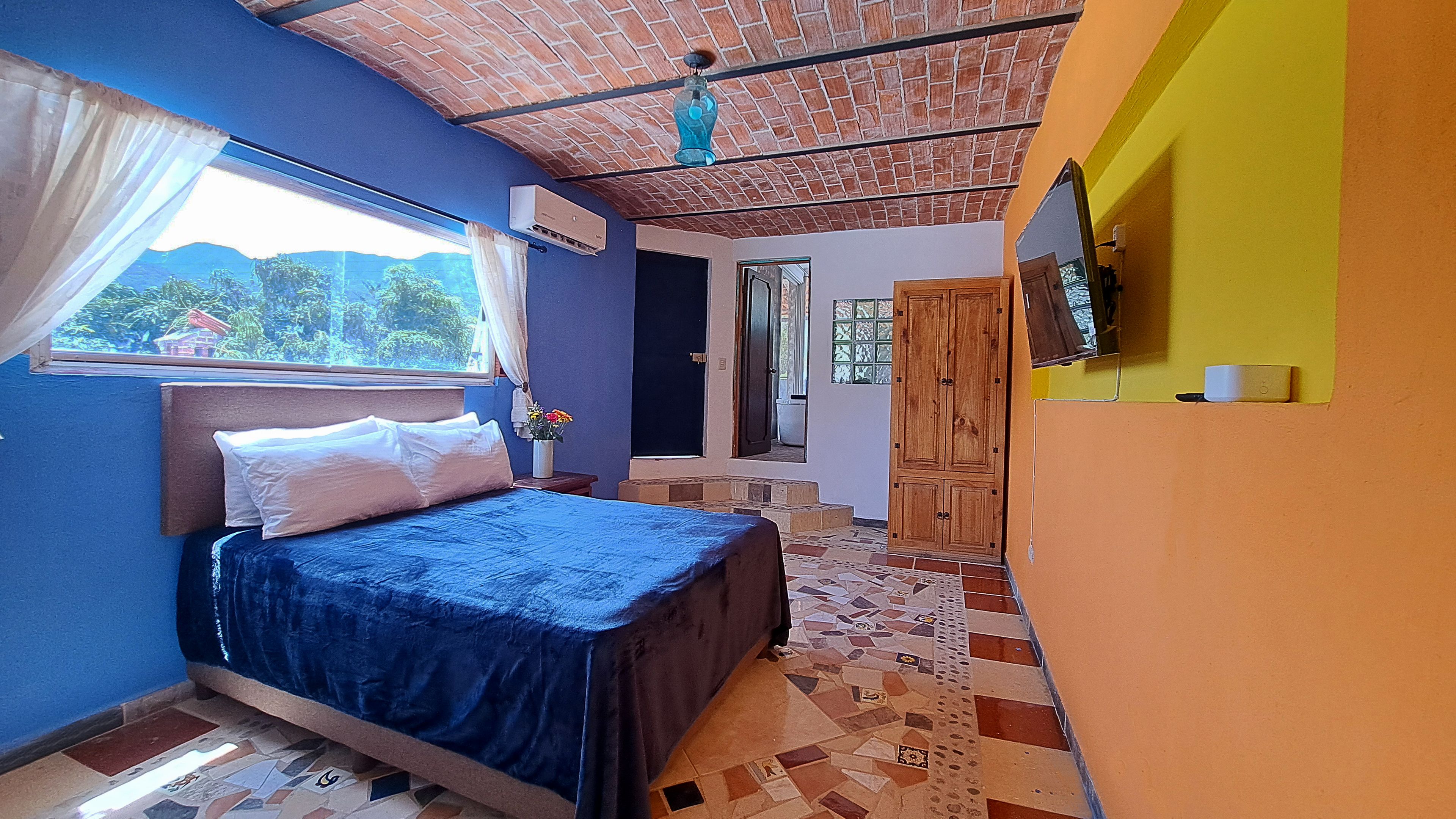 Un dormitorio con una cama, una ventana con cortinas, un ventilador de techo y piso de baldosas.