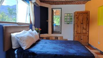 Un dormitorio con una cama, una ventana, un armario de madera y un baño visible a través de una puerta abierta.