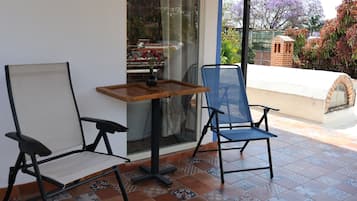 Un balcon avec une table et deux chaises, un sol carrelé et une vue sur les environs.