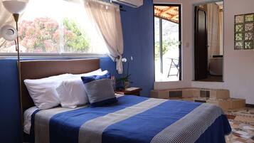 Un dormitorio con cama, ventana con cortinas, equipo de aire acondicionado y vistas al exterior.