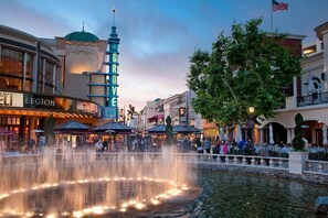 Ett offentligt torg med en fontän, omgivet av byggnader med olika butiker och restauranger.