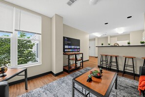 A modern kitchen with a large window, a flat-screen TV, and a bar area with stools. - Spacious 4BR, 2BA Home. Mins to UC Med, Zoo & OTR (Cincinnati)