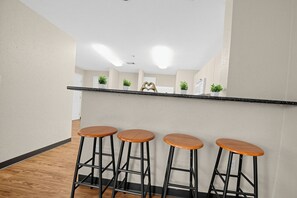 A kitchen area with a countertop, four wooden stools, and potted plants. - Spacious 4BR, 2BA Home. Mins to UC Med, Zoo & OTR (Cincinnati)