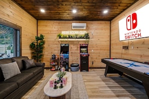 Ein gemütliches Zimmer mit Billardtisch, einer Couch und einem Schild mit Nintendo Switch.
