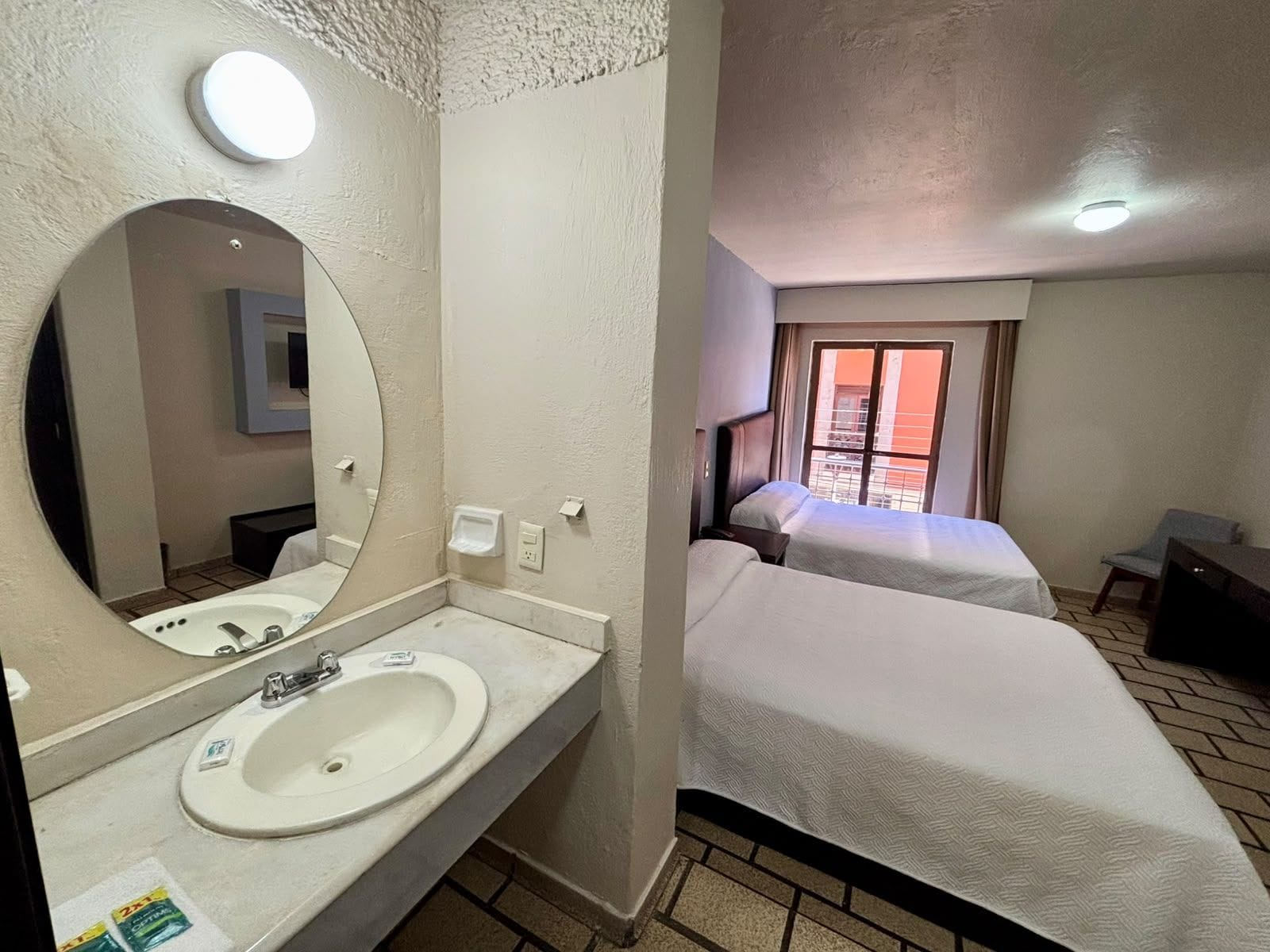 Una habitación de hotel con baño, cama, escritorio y ventana con vistas.