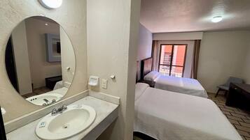 Una habitación de hotel con baño, cama, escritorio y ventana con vistas.
