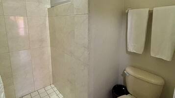 Un baño con ducha, inodoro y perchero para toallas.