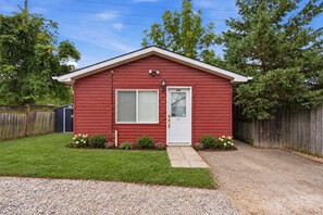 A red single-story house with a front door, a window, and a small porch area. - Rodman Oasis 1BR, 1B with washer/dryer 28+ nights (St. Catharines)