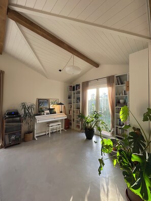 A room with a piano, bookshelves, and potted plants. - A cozy house with a garden, located between the ocean, the Landes region, and the Pyrenees (Angoumé)