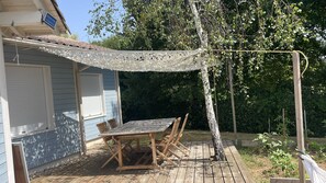 A patio with a table and chairs, a covered area with a patterned canopy, and a tree. - A cozy house with a garden, located between the ocean, the Landes region, and the Pyrenees (Angoumé)