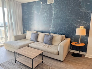 A modern living room with a sofa, a coffee table, and a lamp. - Bright BW Apt - Pool, Gym & Beach Access (Hallandale Beach)