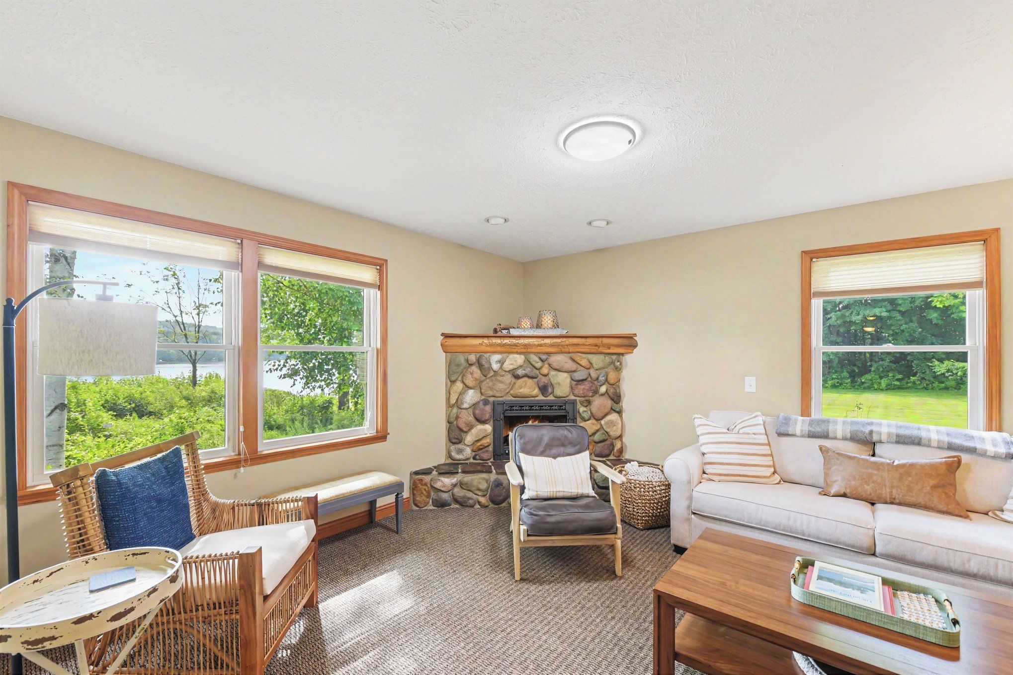 A cozy living room with a stone fireplace, a sofa, a chair, and a table.