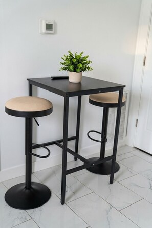A black metal bar stool with a cushioned seat and a small potted plant on top. - 2-bedroom apartment Minutes from NYC (Irvington)