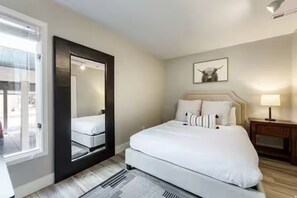 Ein Hotelzimmer mit einem Bett, einem Nachttisch, einem Spiegel, einem Fenster und einem Wandbild.