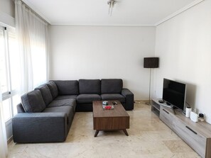 A modern living room with a sectional sofa, a wooden coffee table, a flat-screen TV, and a minimalist design. - Spacious Downtown Apartment with a Jacuzzi (Córdoba)