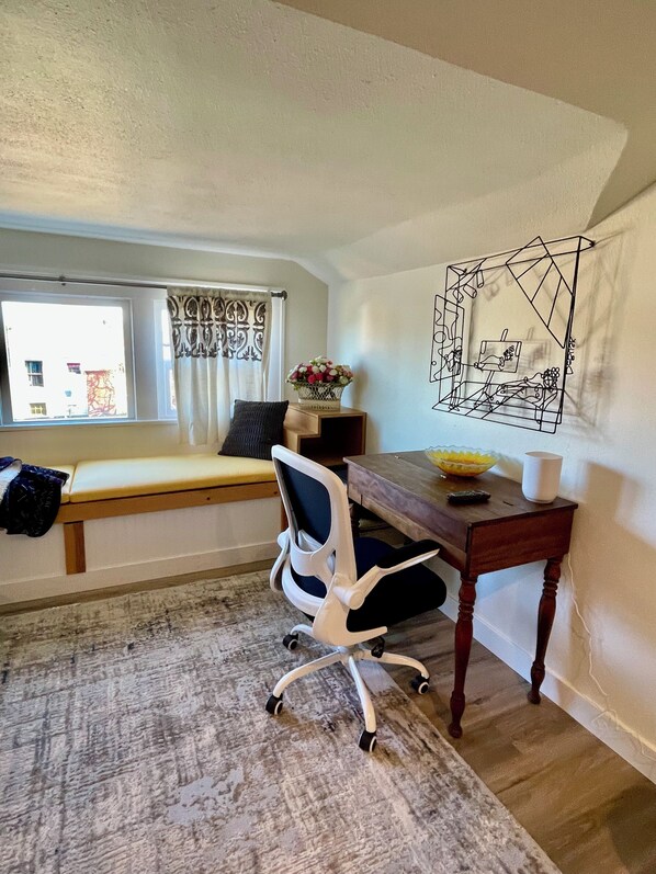 A room with a desk, chair, and a window with curtains.