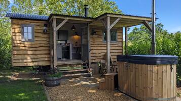 Une cabane en bois dotée d’un porche couvert, d’un jacuzzi et d’une petite cuisine extérieure.