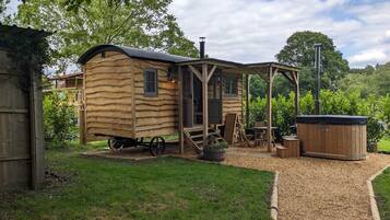 Un chalet rustique en bois doté d’une véranda, d’un bain à remous et d’un petit espace de détente extérieur.