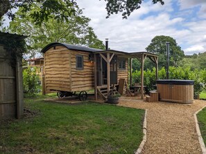 Un chalet rustique en bois doté d’une véranda, d’un bain à remous et d’un petit espace de détente extérieur.
