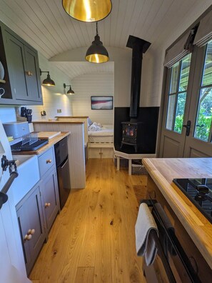 Une cuisine compacte avec un plancher en bois, une cuisinière et un coin repas avec un banc.