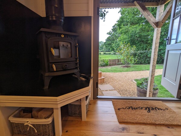 A wood-burning stove in a room with a view of a garden.