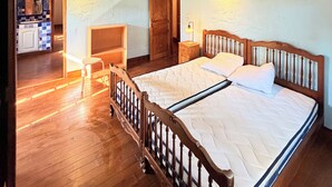 Quarto com cama, soalho e teto de madeira, e porta que dá para um banheiro.