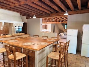 A kitchen with a wooden island, chairs, and a refrigerator. - Authentic, spacious farmhouse in the Camargue, in a quiet location near a castle, with a private pool (Aimargues)