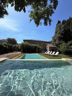A clear swimming pool with lounge chairs and a building in the background. - Authentic, spacious farmhouse in the Camargue, in a quiet location near a castle, with a private pool (Aimargues)