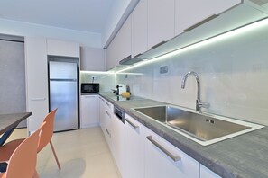 A modern kitchen with stainless steel appliances, a built-in oven, and a large sink. - Bright And Elegant Apartment - Lotis (Dafni)