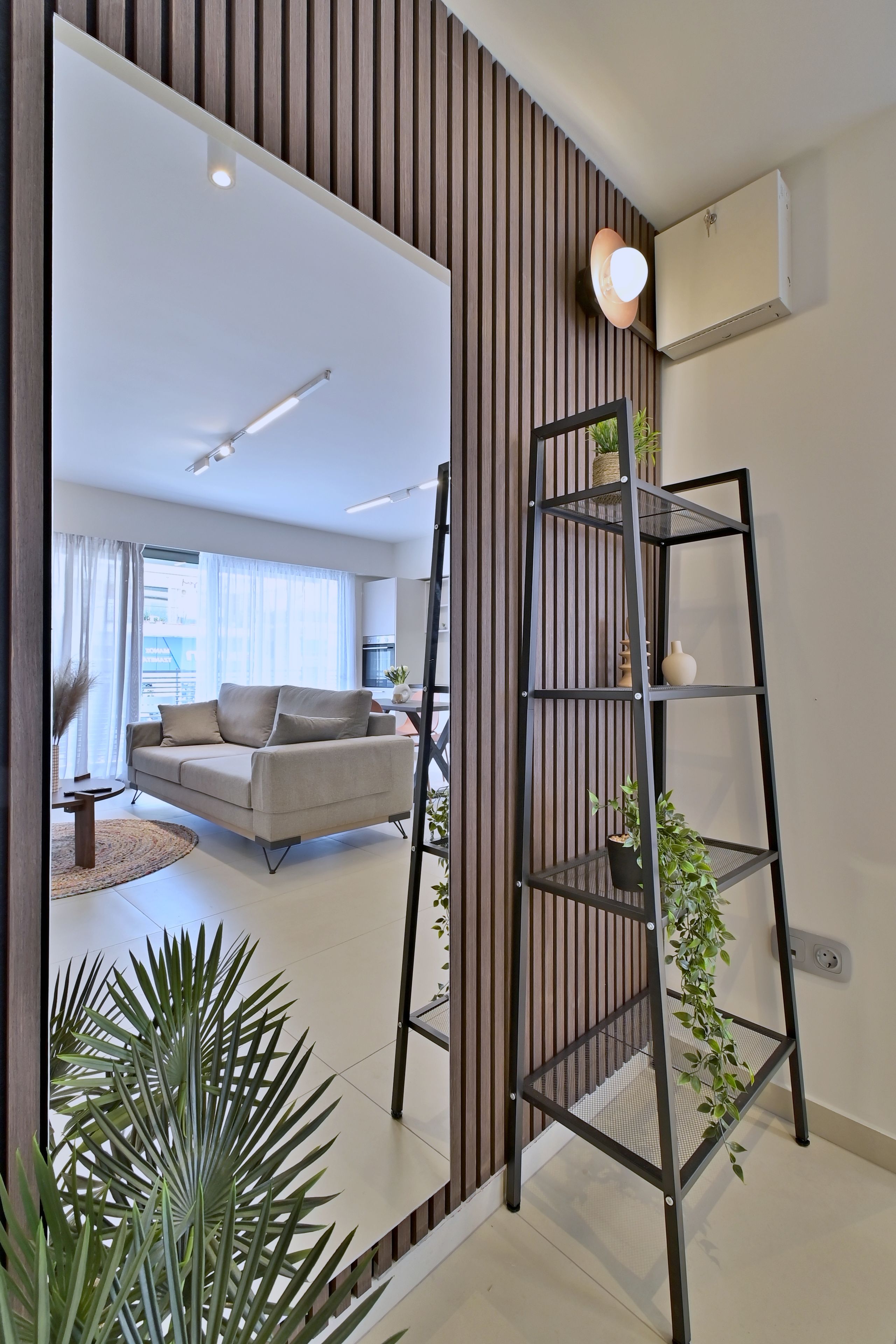 Een moderne woonkamer met een bank, een ladder en een potplant.
