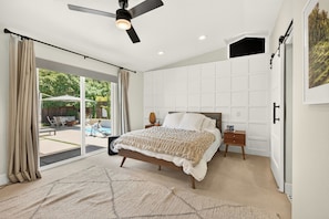 A bedroom with a bed, a ceiling fan, a nightstand, a bedside table, and a view of the outdoors. - Wine Country Escape in the heart of Yountville (Yountville)