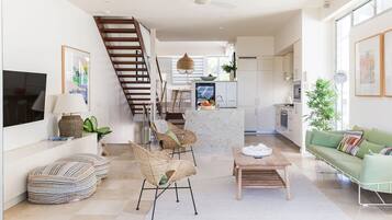 Un ambiente moderno con una scala, un'area pranzo, una cucina e un angolo salotto con divano verde.