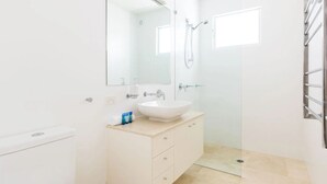 Un bagno con lavandino, specchio e doccia bianchi.