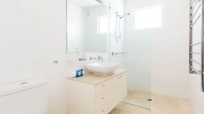 Une salle de bain avec un lavabo blanc, un miroir et une douche.