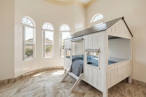A bunk bed room with a view of a mountainous landscape through large arched windows.