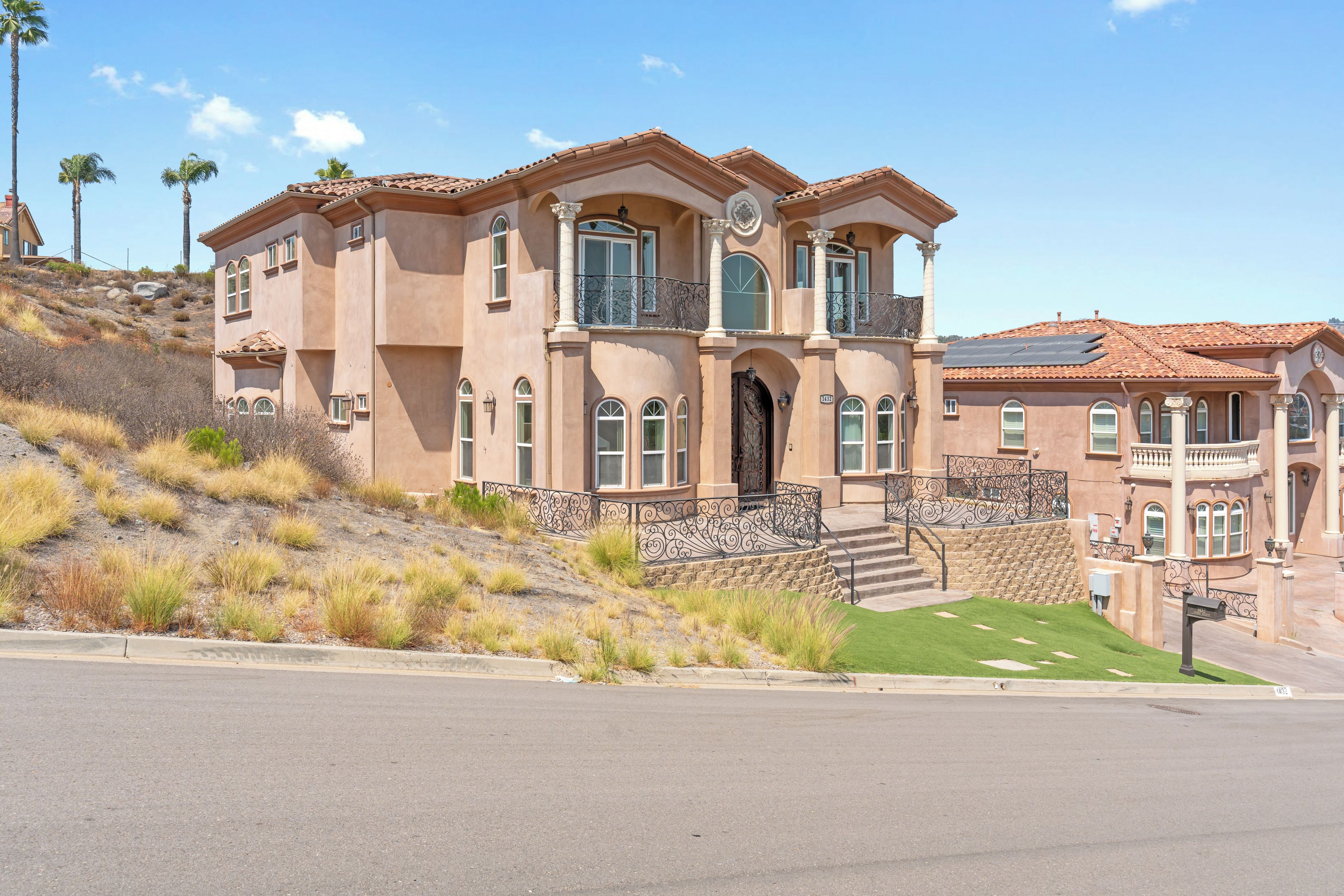 A large, two-story house with a prominent entrance, multiple windows, and a balcony.
