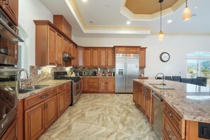 A modern kitchen with wooden cabinets, stainless steel appliances, and a marble floor.