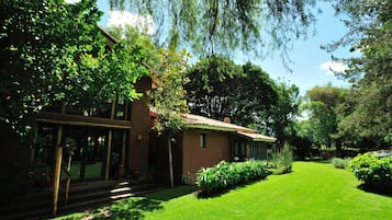 Ein Haus mit gepflegtem Rasen, einem Holzzaun und einem Garten mit verschiedenen Pflanzen.