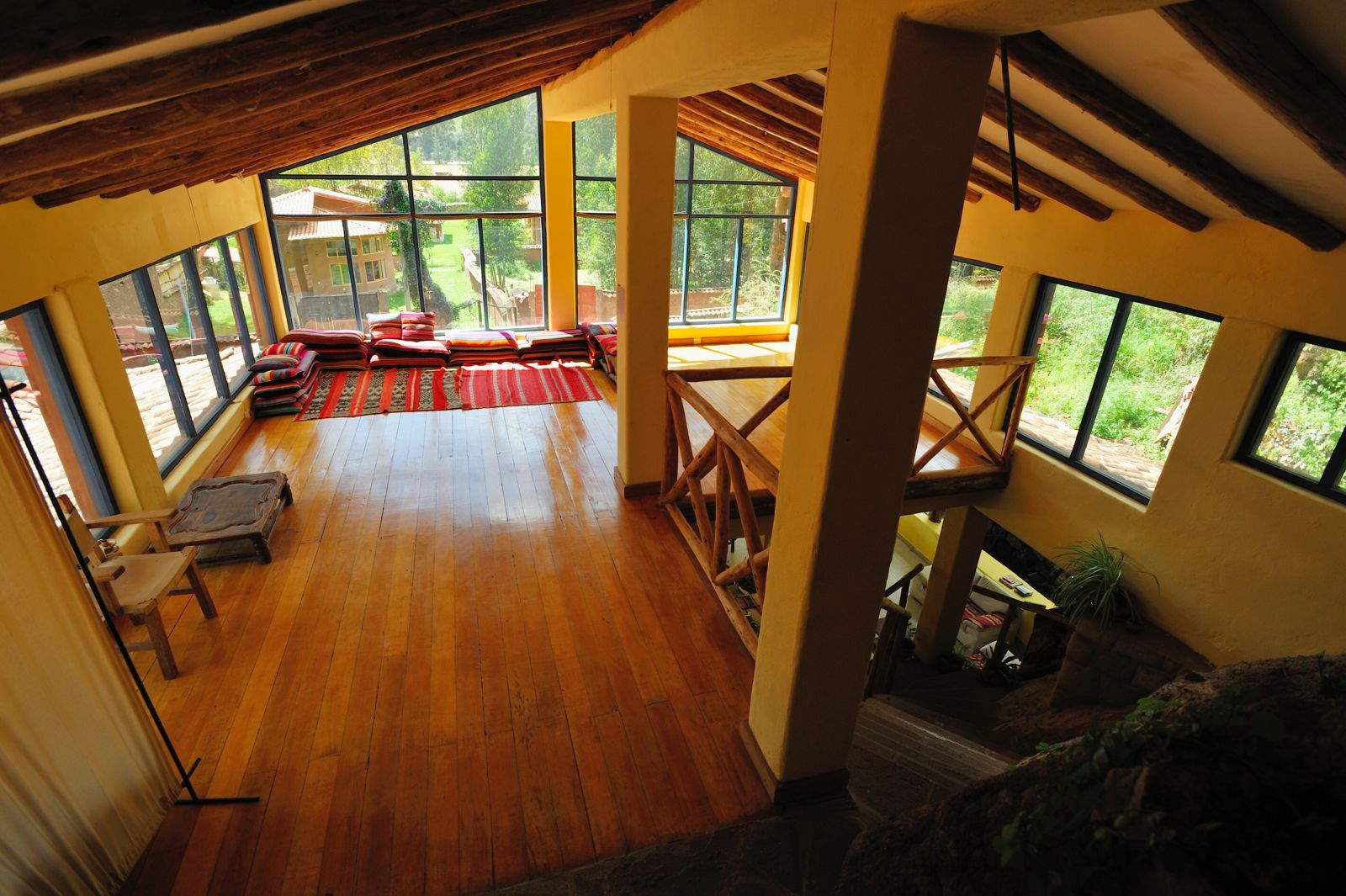 Una habitación amplia con suelo de madera, ventanas grandes y vistas al exterior.