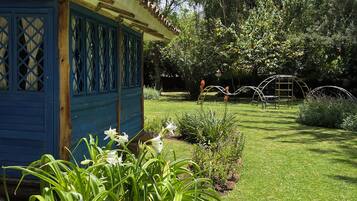 Ein blaues Gebäude mit einem Garten davor, inklusive Rasen und verschiedenen Pflanzen.