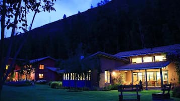 Un immobile residenziale con un prato curato, un patio con posti a sedere e una casa con molte finestre e un camino ben visibile.