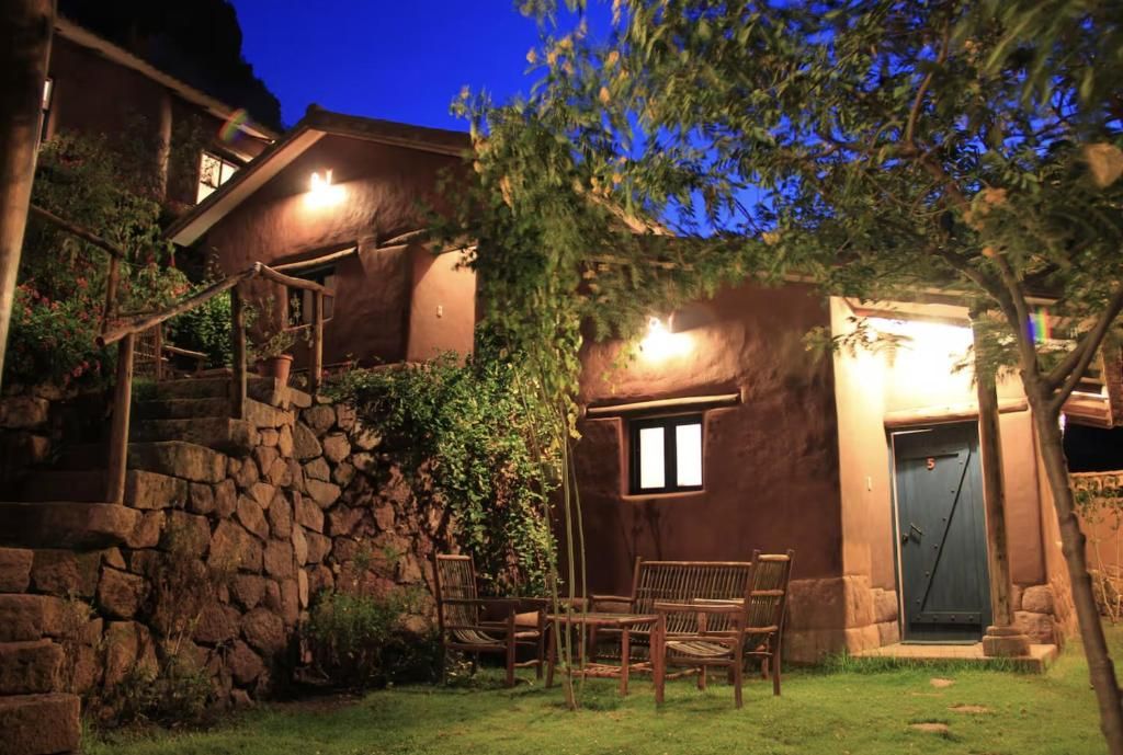 Un bâtiment rustique doté d’un escalier en pierre, d’une porte et de mobilier d’extérieur.