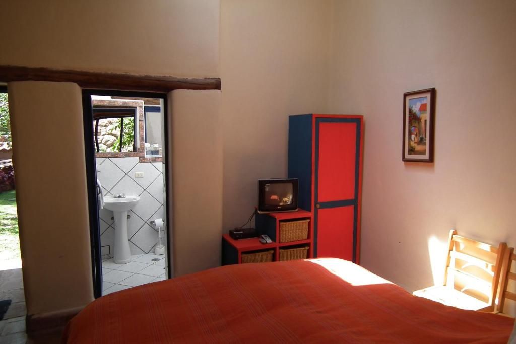 A bedroom with a bed, a television, a wardrobe, and a window.