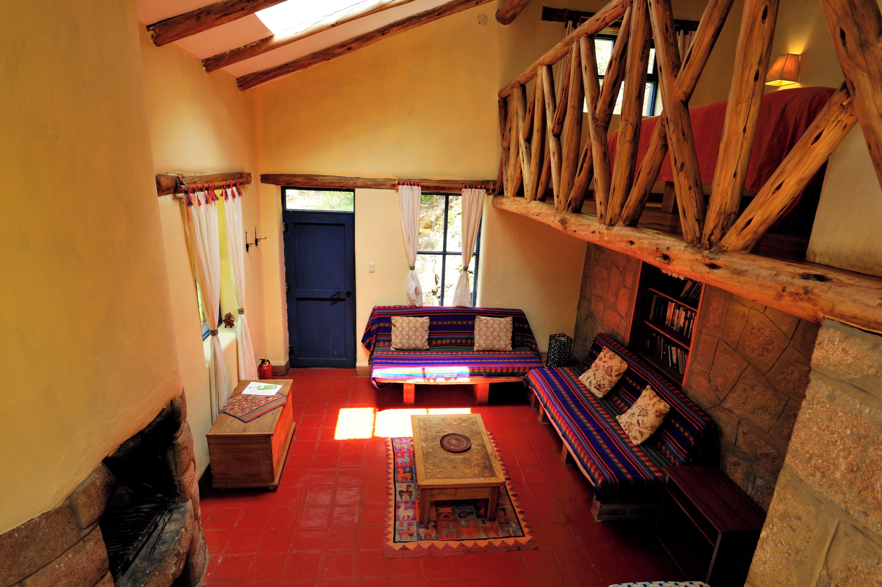 Una habitación acogedora con techo de madera, un conjunto de sofás, una mesita y una estantería.